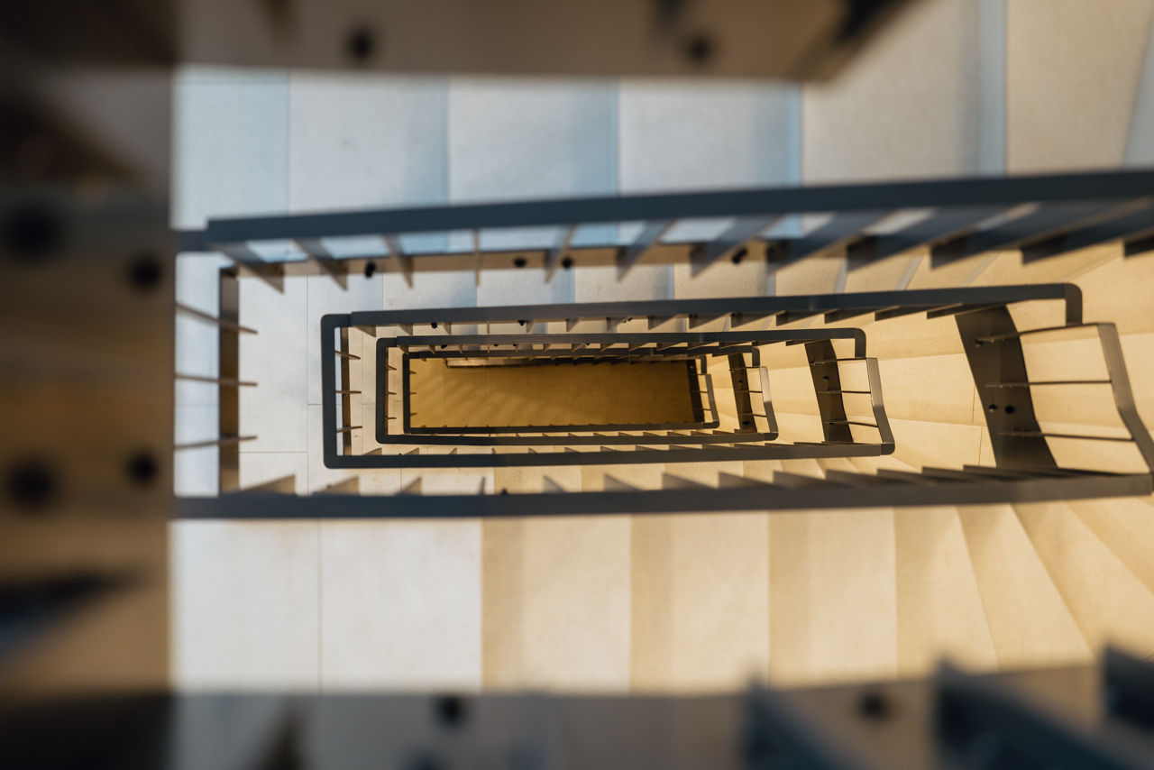 Blick von oben in ein modern gestaltetes Treppenhaus des Wohnprojekts ELMLAND1 mit hellen Stufen, klaren Geländerlinien und gleichmäßiger Beleuchtung. Die Aufnahme zeigt einen funktionalen und barrierearmen Erschließungsbereich innerhalb des Gebäudes.