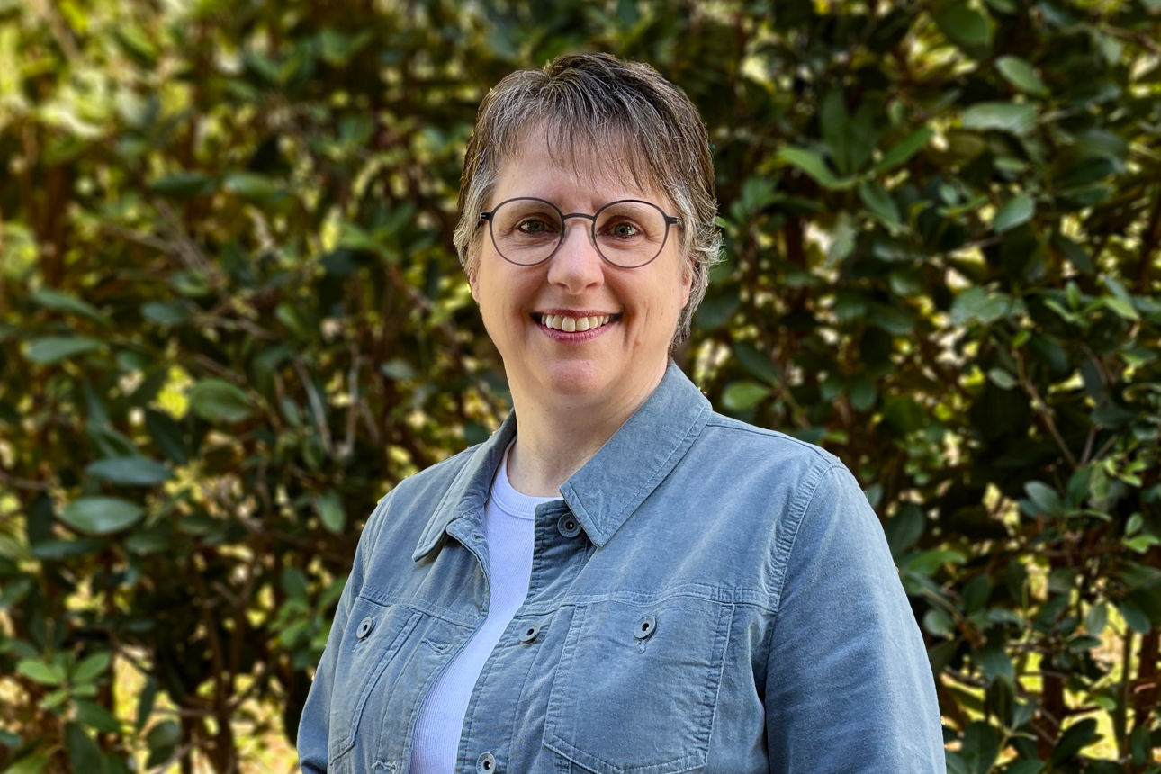 Elsbeth Stratmann stehend vor einer Hecke