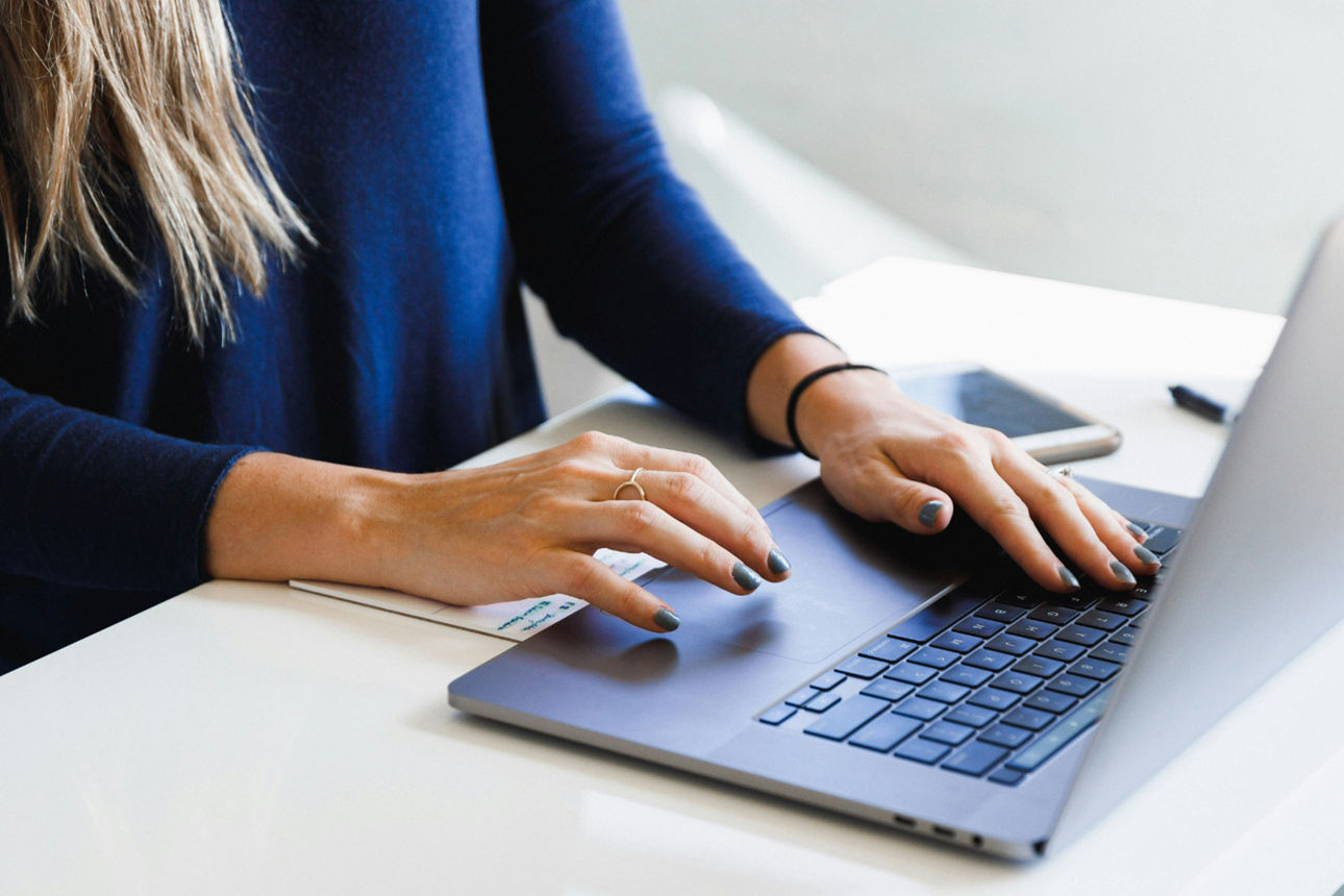 Junge Frau sitzt am Laptop und tippt auf der Tastatur
