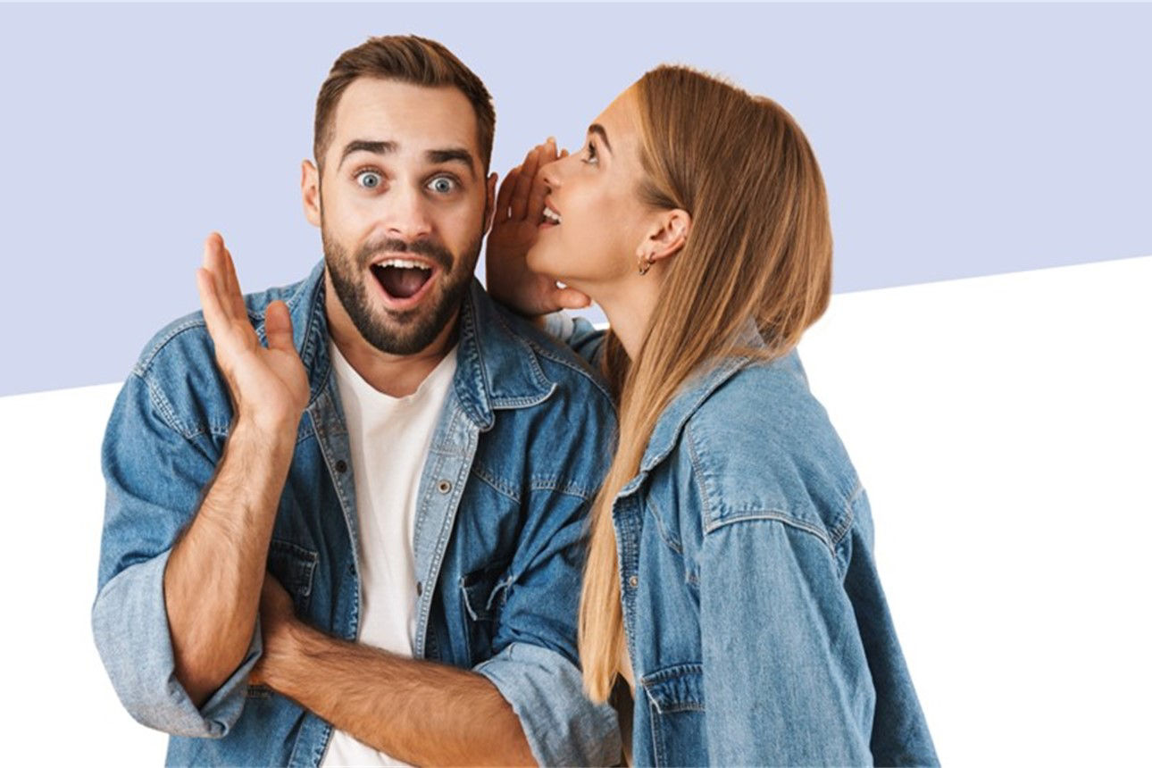 Eine Frau flüstert einem Mann etwas ins Ohr