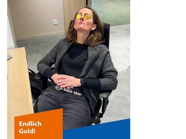 Eine Frau lehnt sich in einem Schreibtischstuhl zurück, auf ihren geschlossenen Augenlidern liegen Goldmünzen