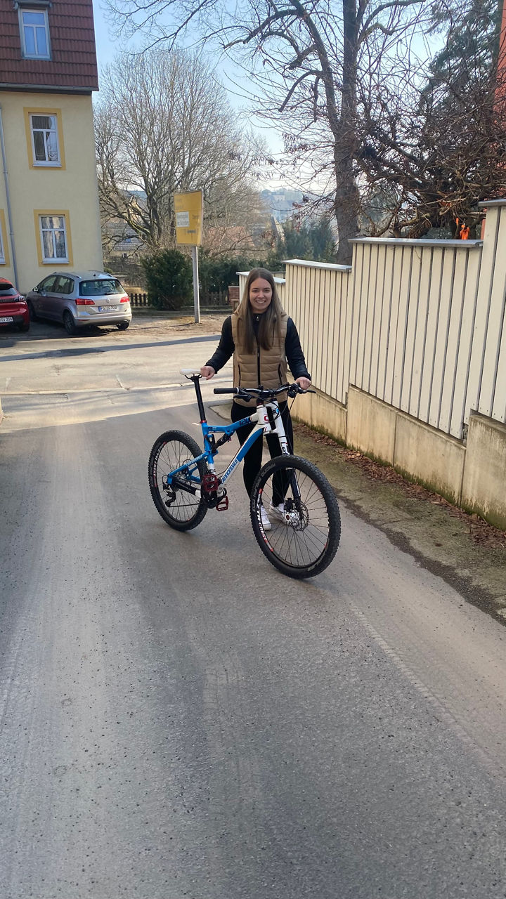 Frau mit Fahrrad auf einer Straße: Für kurze Strecken lasse ich das Auto stehen und schwinge mich aufs Fahrrad.