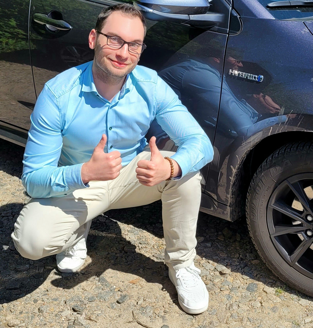 Mann im blauen Hemd und weißer Hose vor blauem Auto: Seit fast 4 Jahren fahre ich ein Hybridauto