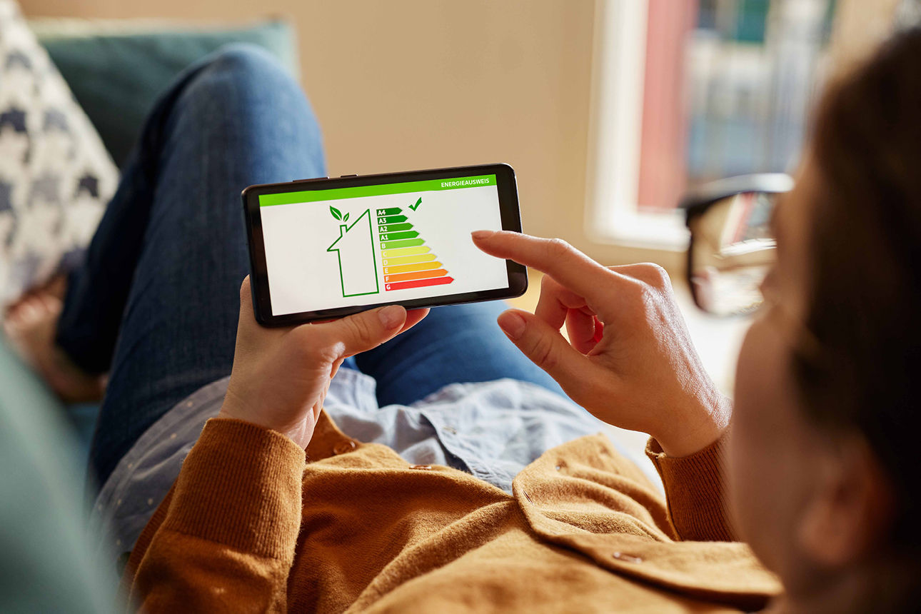 Eine Frau shcaut auf ihr Handy, auf welchem ein Energieausweis zu sehen ist.