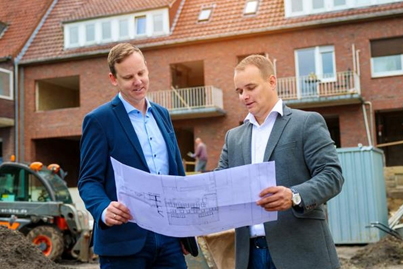 Energieberater Michael Vettel und Gerrit Schöpper mit Bauplan vor einem Bauprojekt
