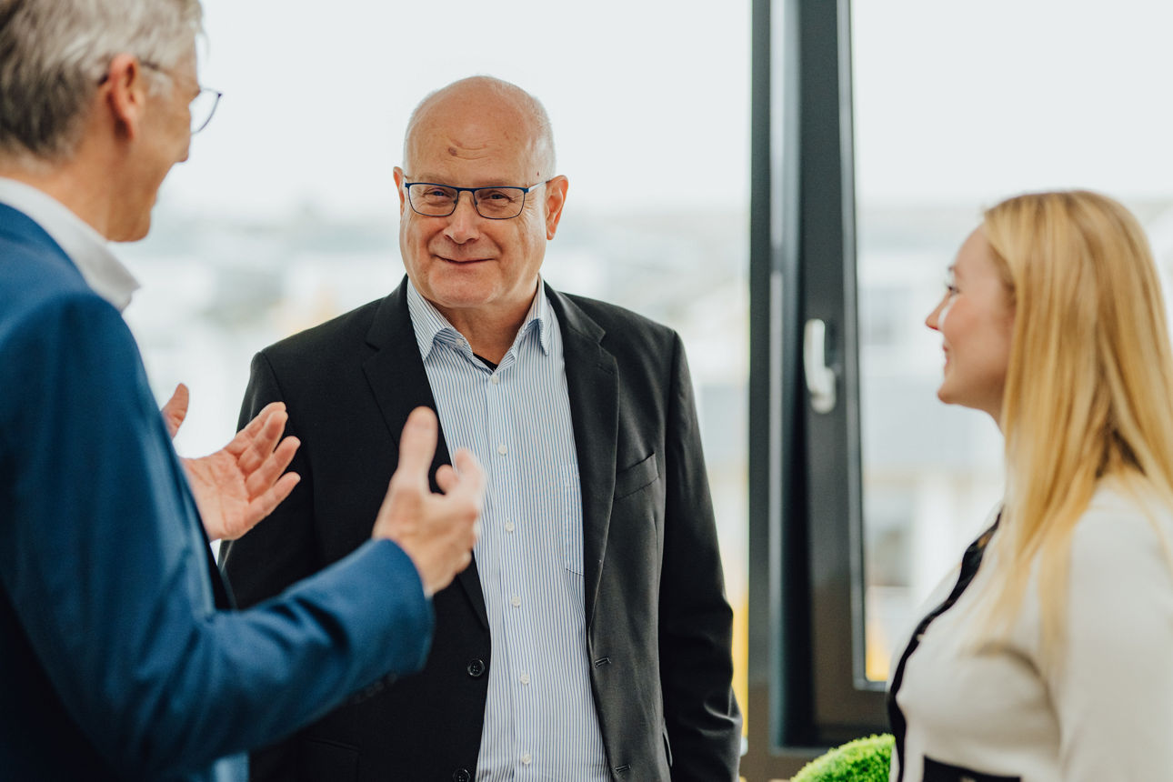 Drei Mitarbeitende führen ein Gespräch in einem Büro