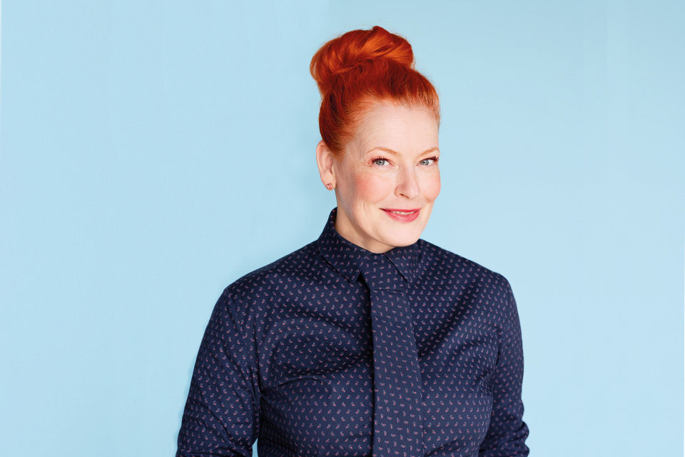 Eine Dame steht vor einem blauen Hintergrund