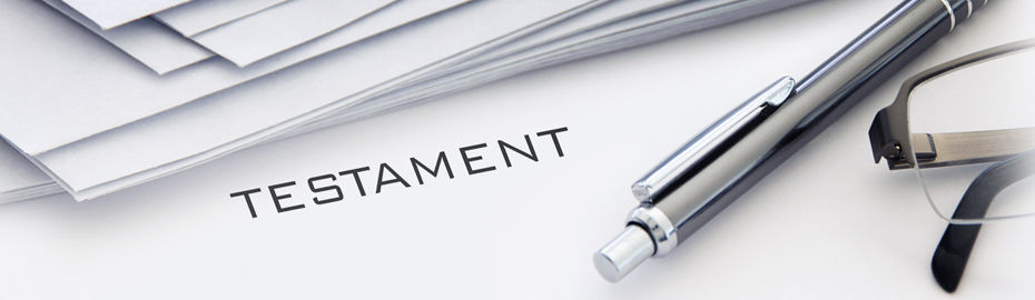 Ein Kugelschreiber und eine Brille liegen auf einem Papier auf dem Testament steht