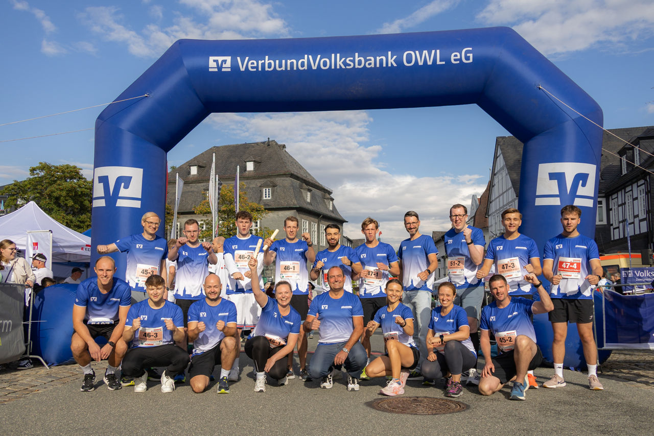 Mitarbeiterinnen und Mitarbeiter der Volksbank Brilon im einheitlichen Laufshirt vor dem Zieleinlauf