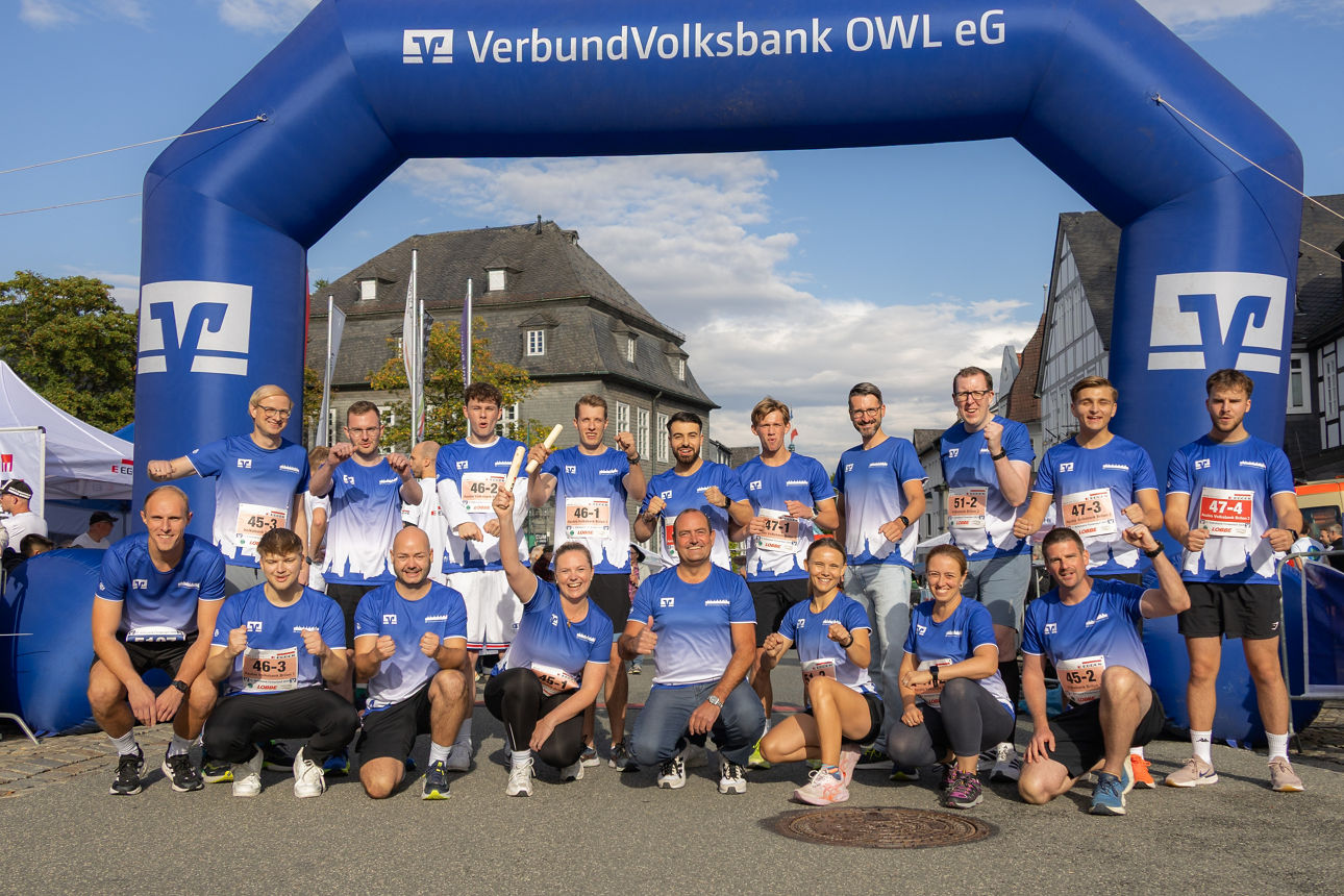 Mitarbeiterinnen und Mitarbeiter der Volksbank Brilon im einheitlichen Laufshirt vor dem Zieleinlauf