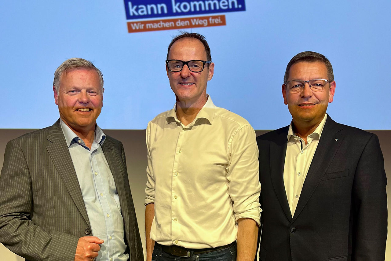 Drein Herren stehen vor hellblauem Hintergrund. In der Mitte der Kabarettist Vince Ebert, links Reinhard Schwaiger, rechts Bernhard Nickel (beide  Vorstände der FS-Bank)