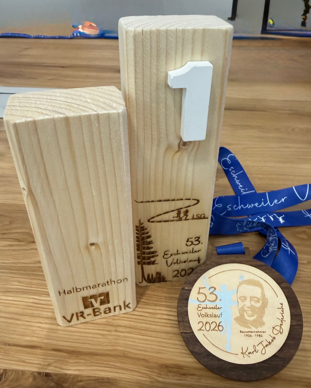 Pokale und Finisher-Medaille, die das Porträt des Eschweiler Bauunternehmers Karl Jakob Dederichs zeigt.