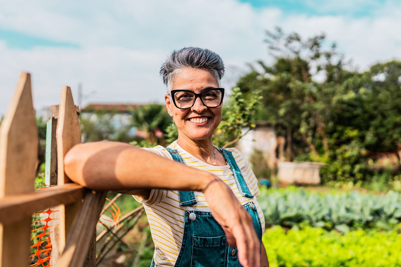 Frau steht  auf einem Feld und lacht in die Kamera