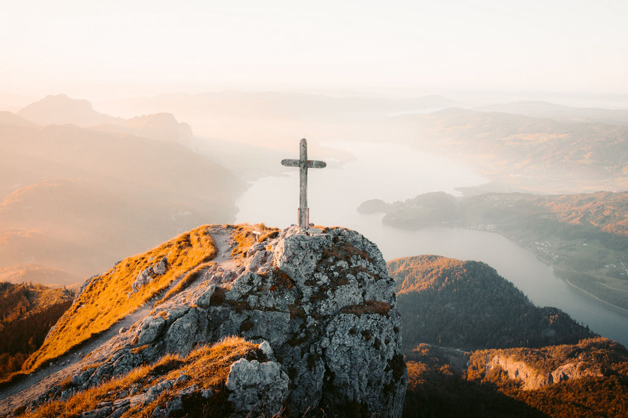Ein Kreuz steht auf einem Berg im Sonnenaufgang
