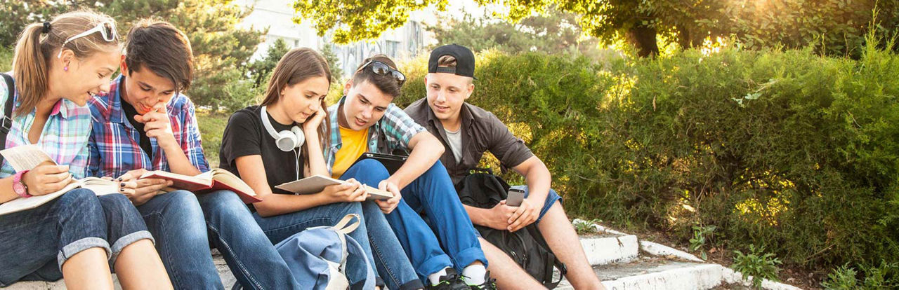 Mehrere Kinder sitzen zusammen auf einer großen Treppe und lesen