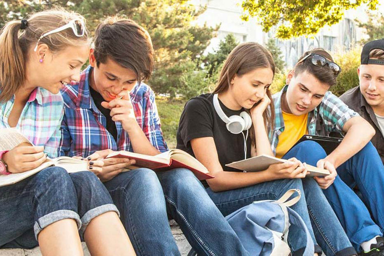 Mehrere Kinder sitzen zusammen auf einer großen Treppe und lesen
