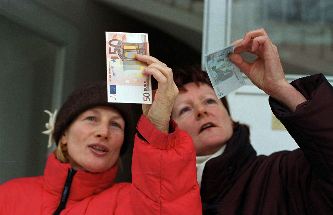 Zwei Frauen betrachten Euroscheine, die sie vor sich in die Luft halten
