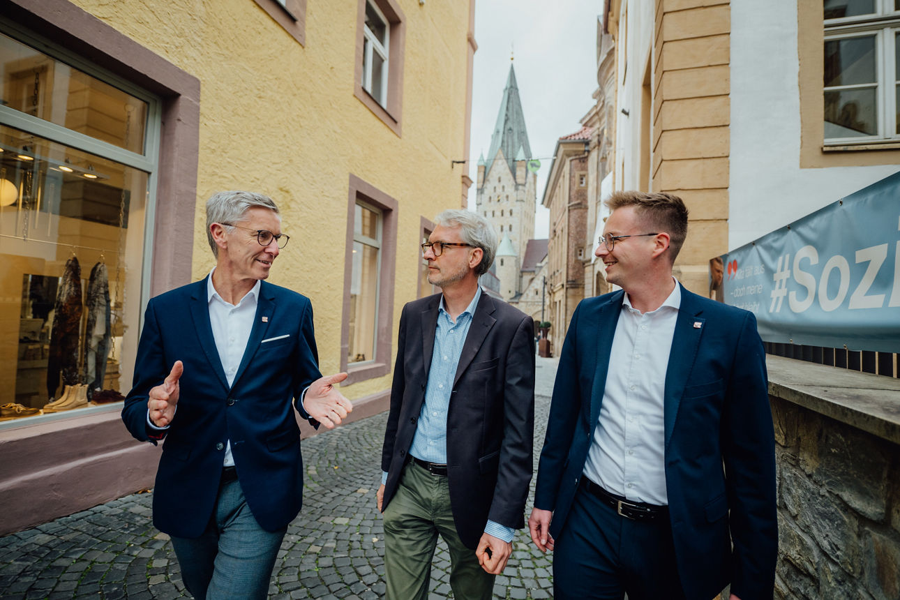 Drei Mitarbeitende laufen durch Paderborn und unterhalten sich