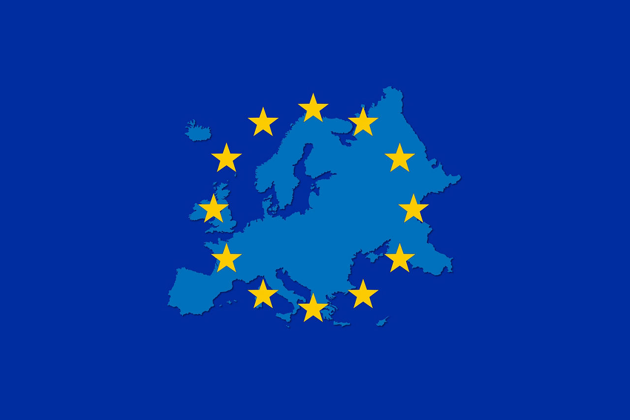 Auf dunkelblauem Untergrund sieht man die hellblauen Umrisse von Europa. Im Kreis darüber angeordnet sind die 12 symbolischen Sterne. 