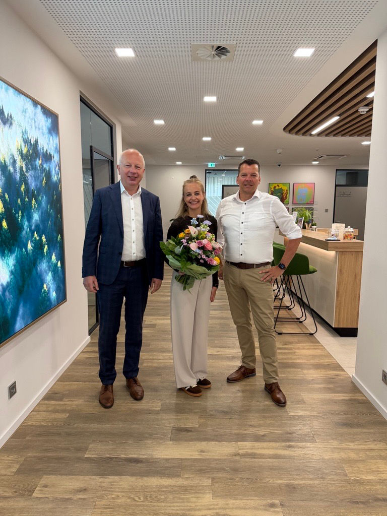 Mehrere Personen haben sich zum Foto aufgestellt. Eine Frau in der Mitte hat einen Blumenstrauß.
