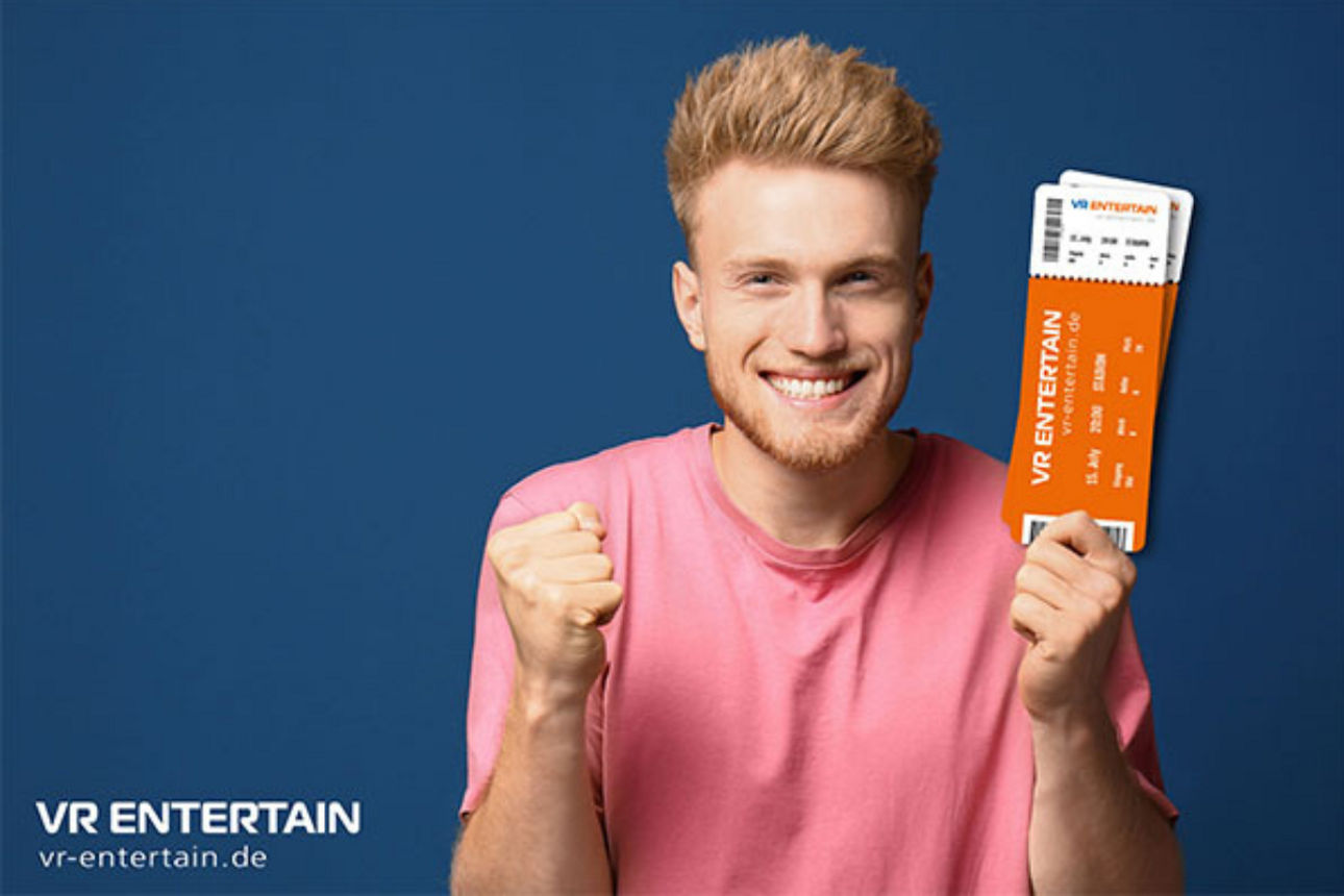 Das Bild zeigt einen jungen Mann mit Eintrittskarten in der Hand