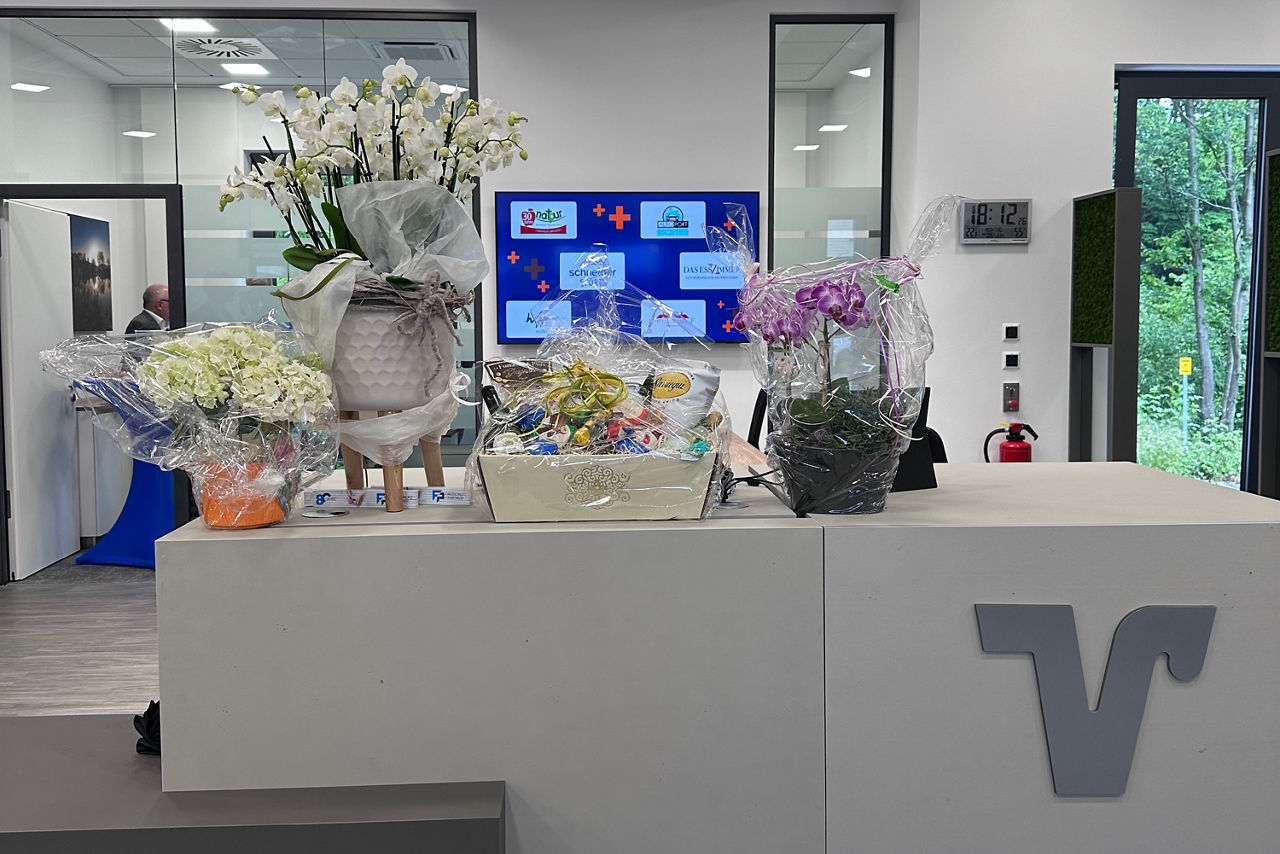 Empfang mit Blumen, Tresen und Bildschrim