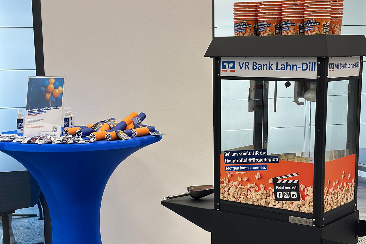 Stehtisch mit blauer Husse und Geschenken, Popcorn-Maschine