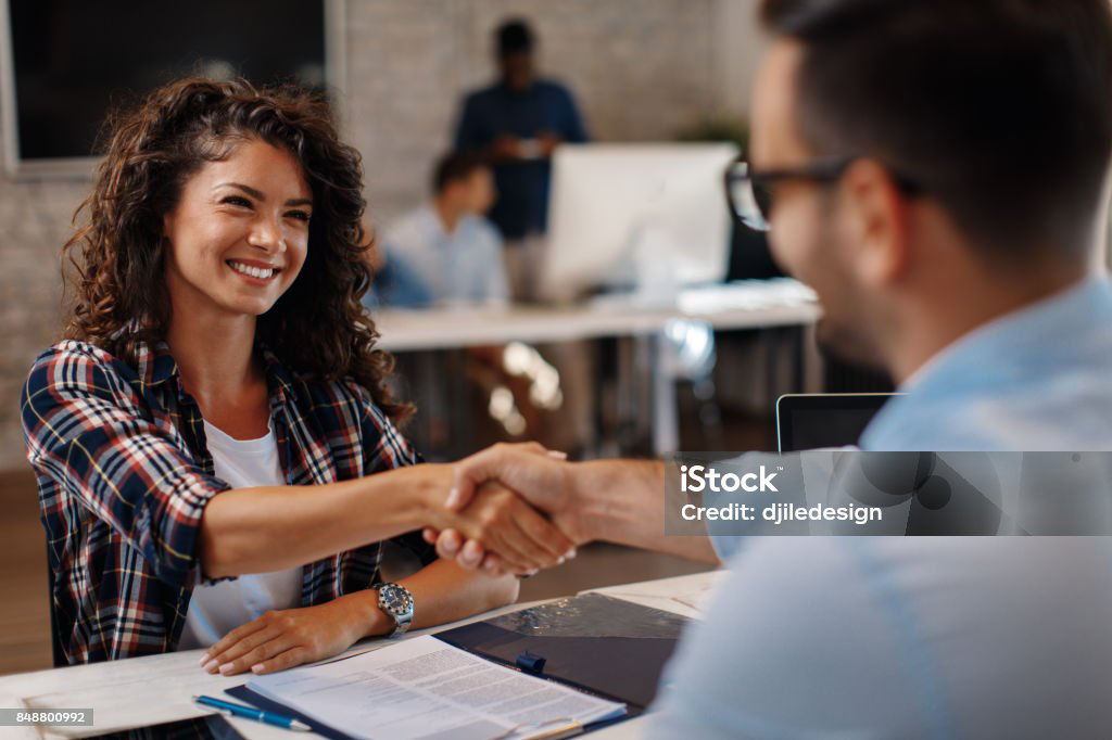 Young woman signing contracts and handshake with a manager