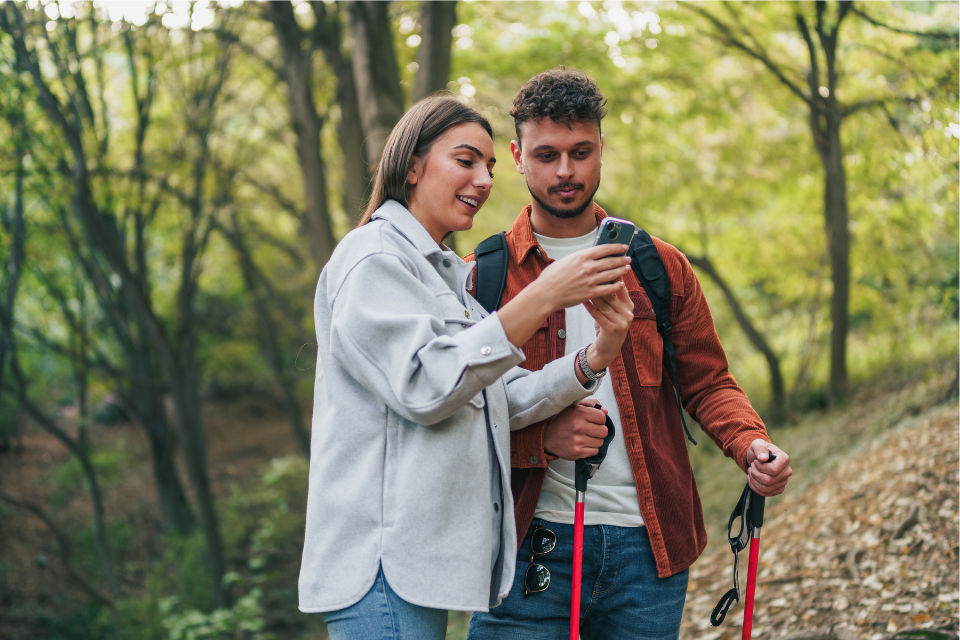 Ein Paar schaut auf Ihr Handy und erkundigt mithilfe der Natur Digital App den Wald. 