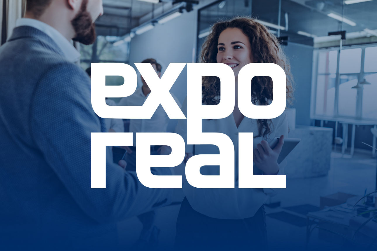 Schriftzug Expo Real und im Hintergrund Gespräch zwischen Frau und Mann