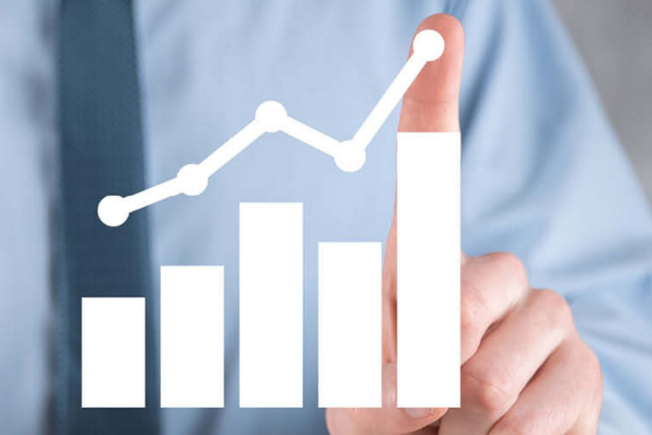 Ein Mann in einem Geschäftsanzug hält ein Diagramm auf einem Tisch und analysiert Daten