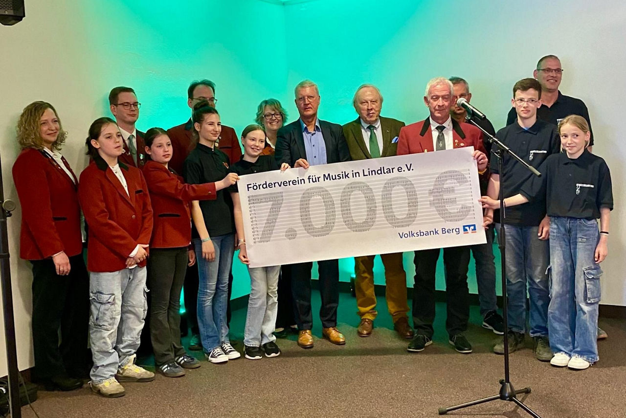 Helmut Vilmar, Vorstand Volksbank Berg, überreicht Werner Sülzer und den Jugendmusikern einen Scheck