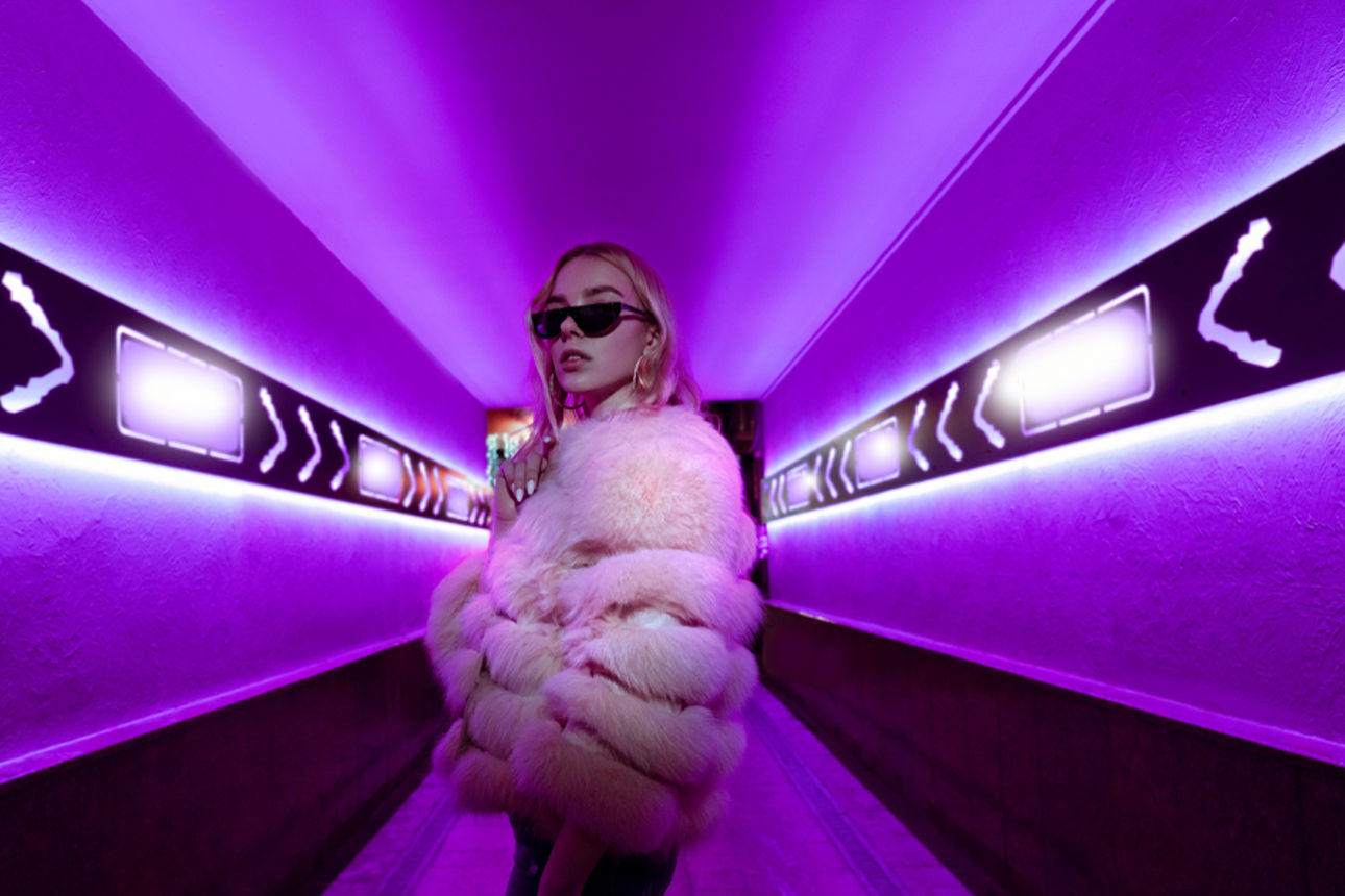 Eine junge Frau steht in einem Flur im lila Licht