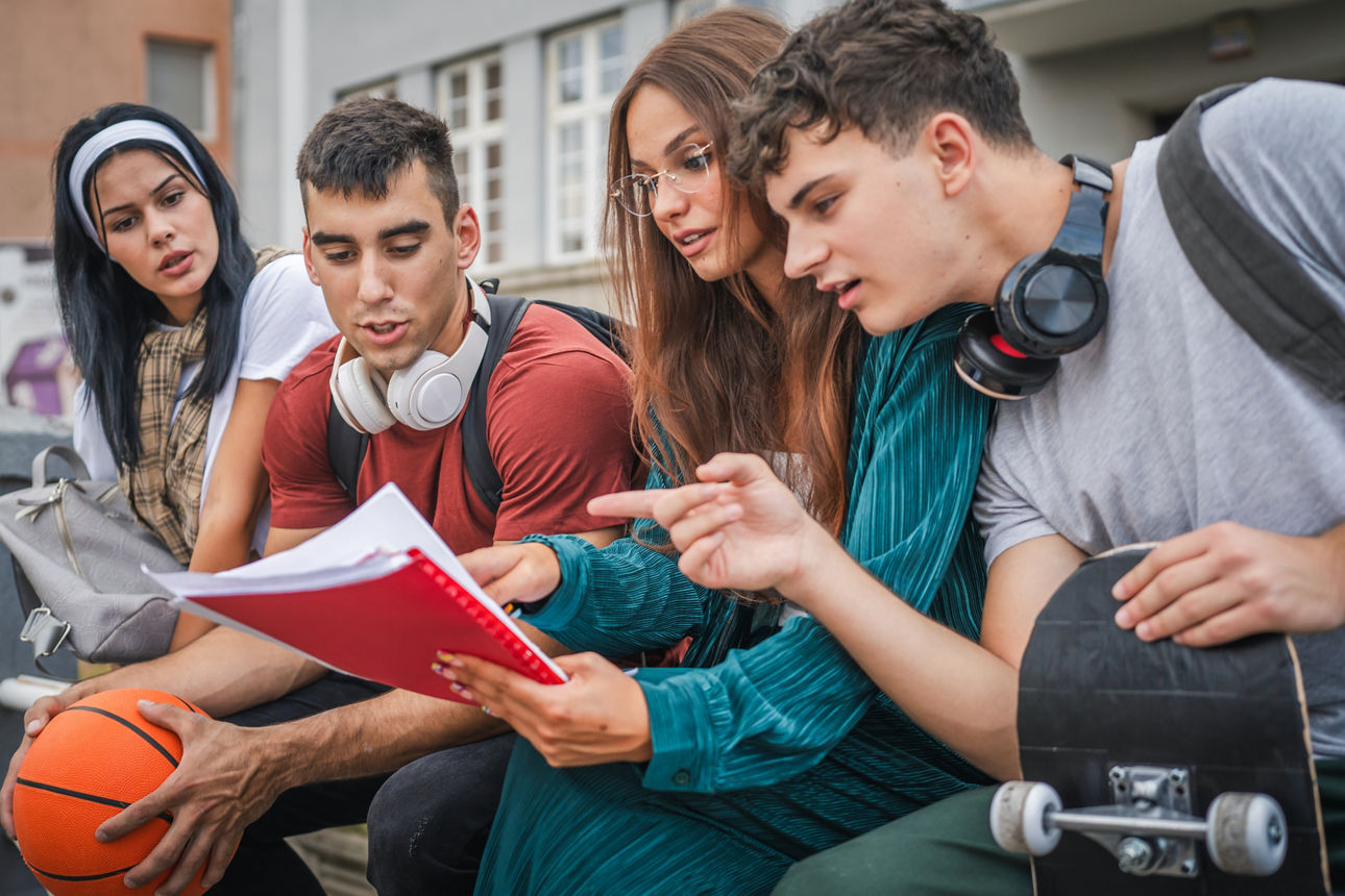 Vier Jugendliche lesen sich zusammen Unterlagen durch