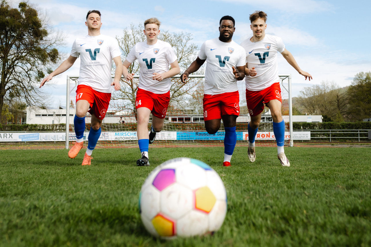 Vier Fußballer laufen auf einen Ball zu.