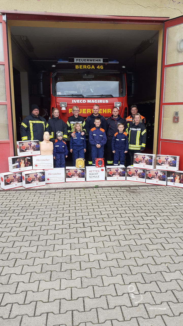 Gruppenbild vor Feuerwehreinsatzwagen mit (Jugend-)Feuerwehrleuten
