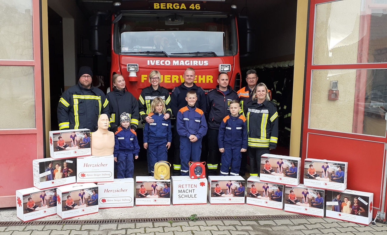 Gruppenbild vor Feuerwehreinsatzwagen mit (Jugend-)Feuerwehrleuten