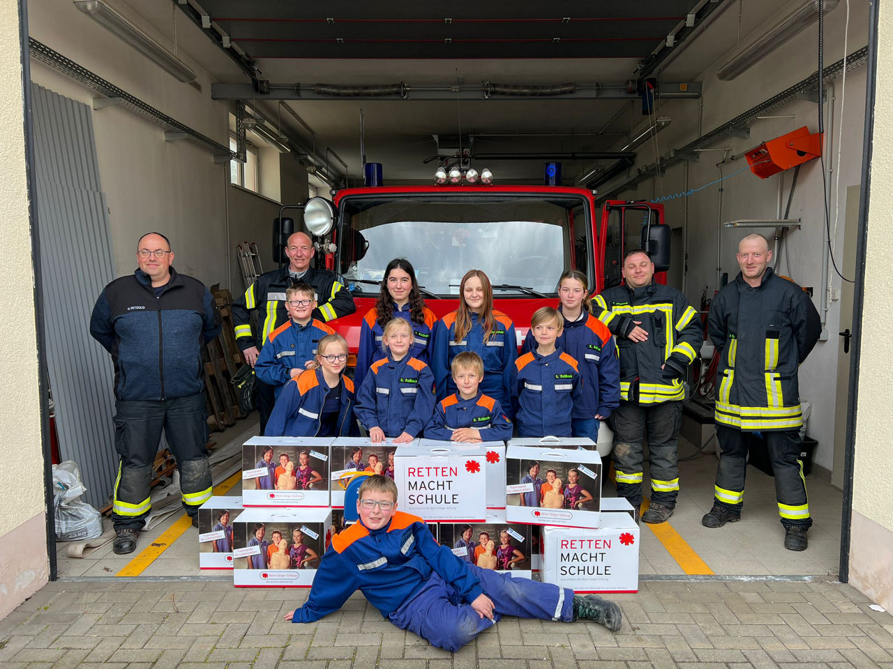 Gruppenbild vor Feuerwehreinsatzwagen mit (Jugend-)Feuerwehrleuten