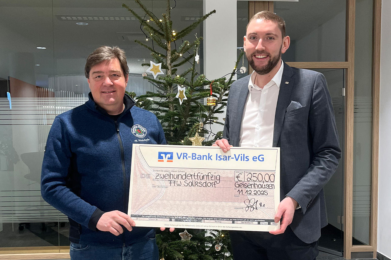 Zwei Männer lächeln in die Kamera. Sie halten einen Riesenspendenscheck in der Hand.