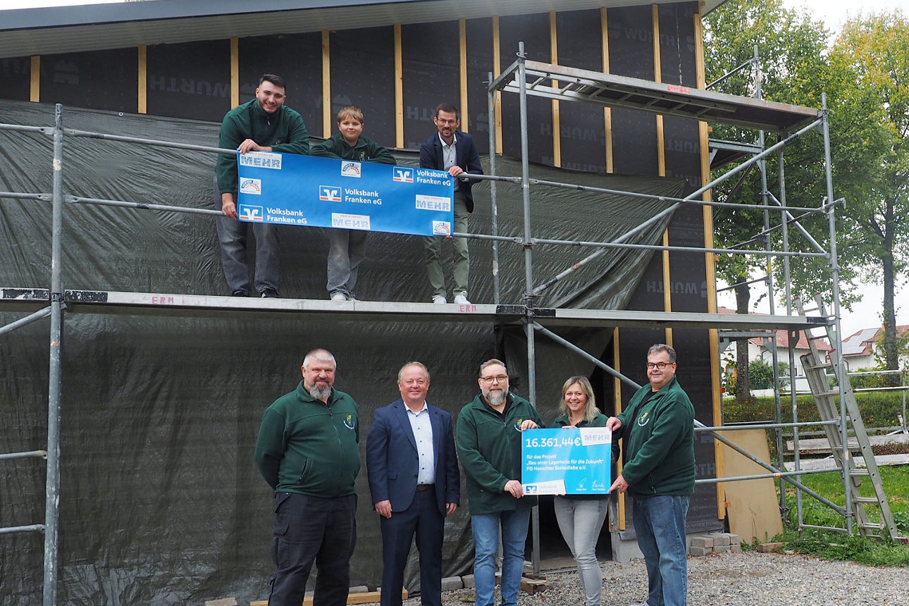Mehrere Personen stehen bei der Spendenübergabe vor einem Neubau