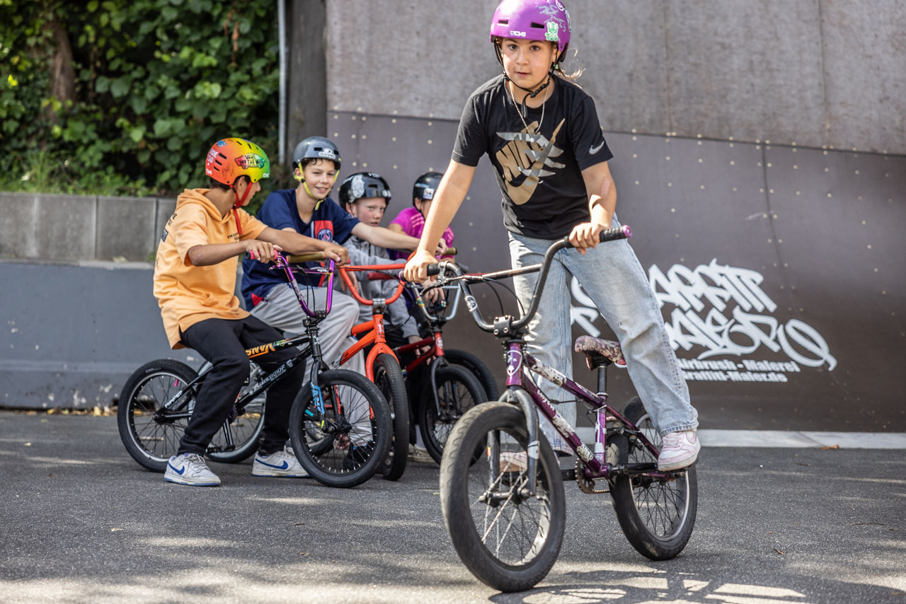 Ein Mädchen fährt auf einem BMX-Fahrrad durch einen BMX-Park.