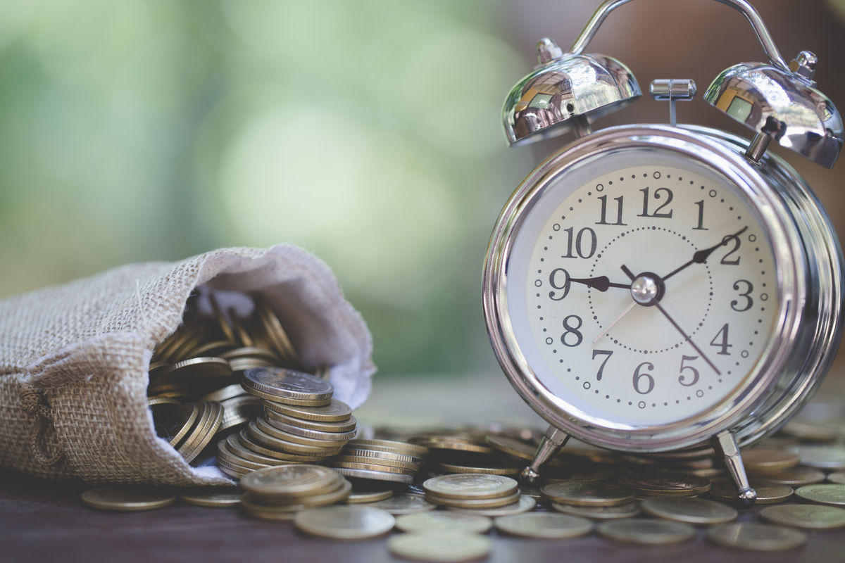 Money bags and  clock on wooden table with nature background,  Money savings,  Stacking growing coins, Saves money for the future, Time investment use money for work.