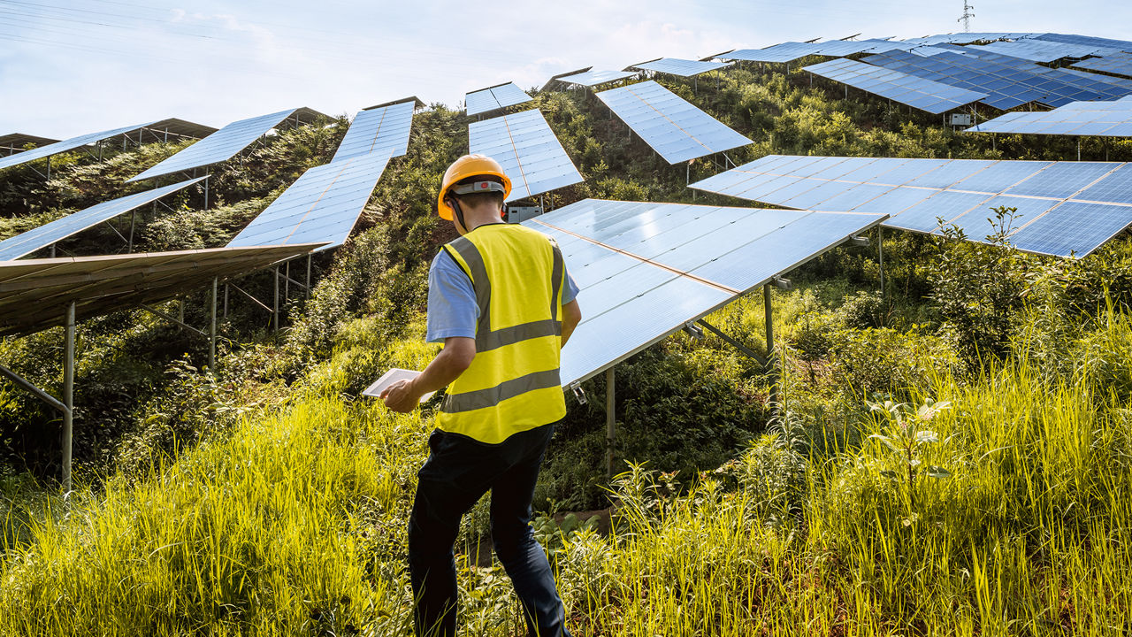 Ingenieur arbeitet an einer großen Solaranlage auf einem Hügel.