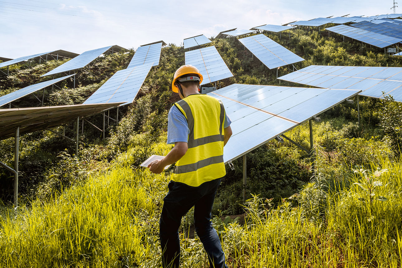 Ingenieur arbeitet an einer großen Solaranlage auf einem Hügel.