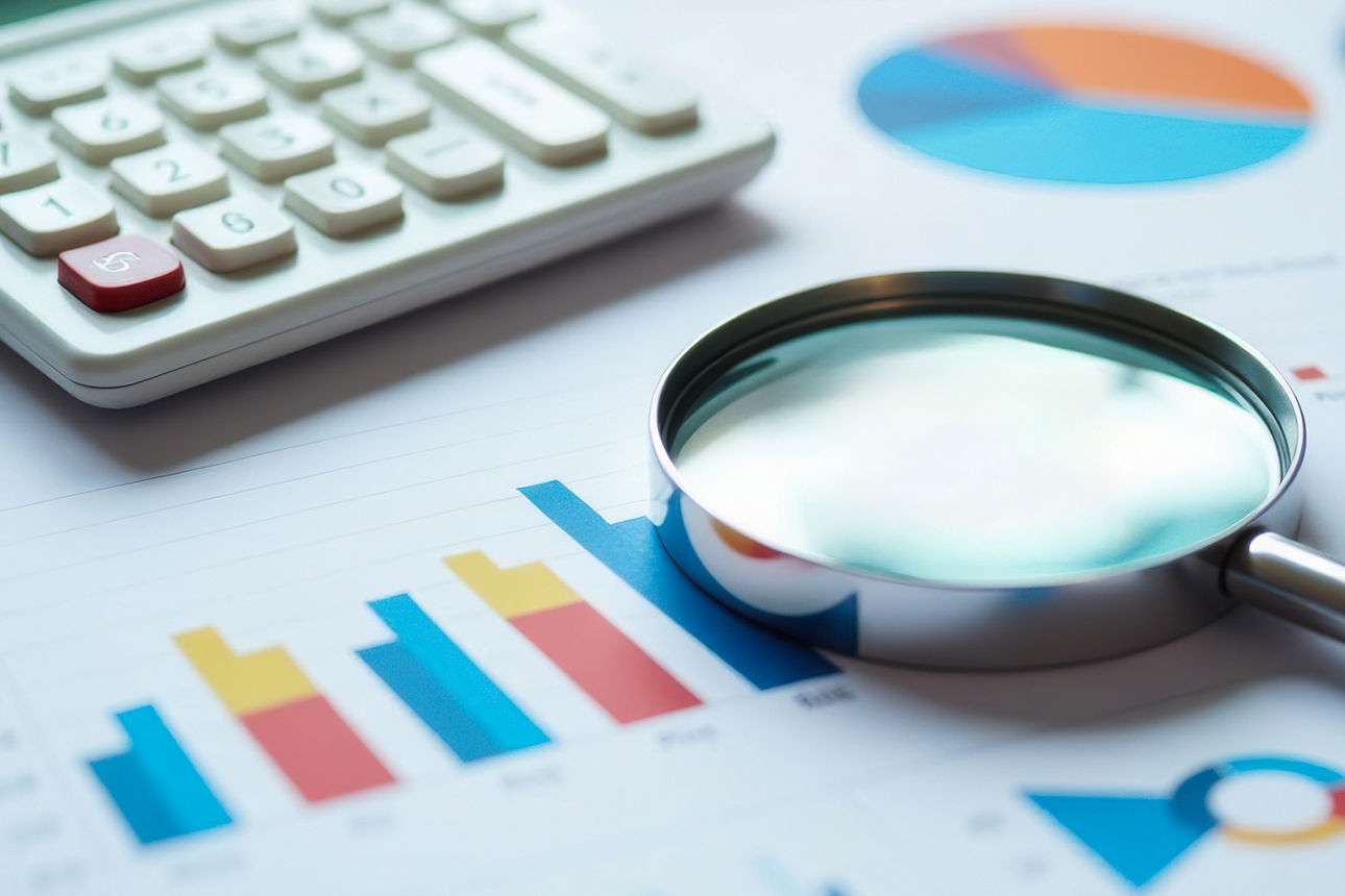 Taschenrechner, Lupe, Stift, Farbdiagramme liegen auf einem Holztisch