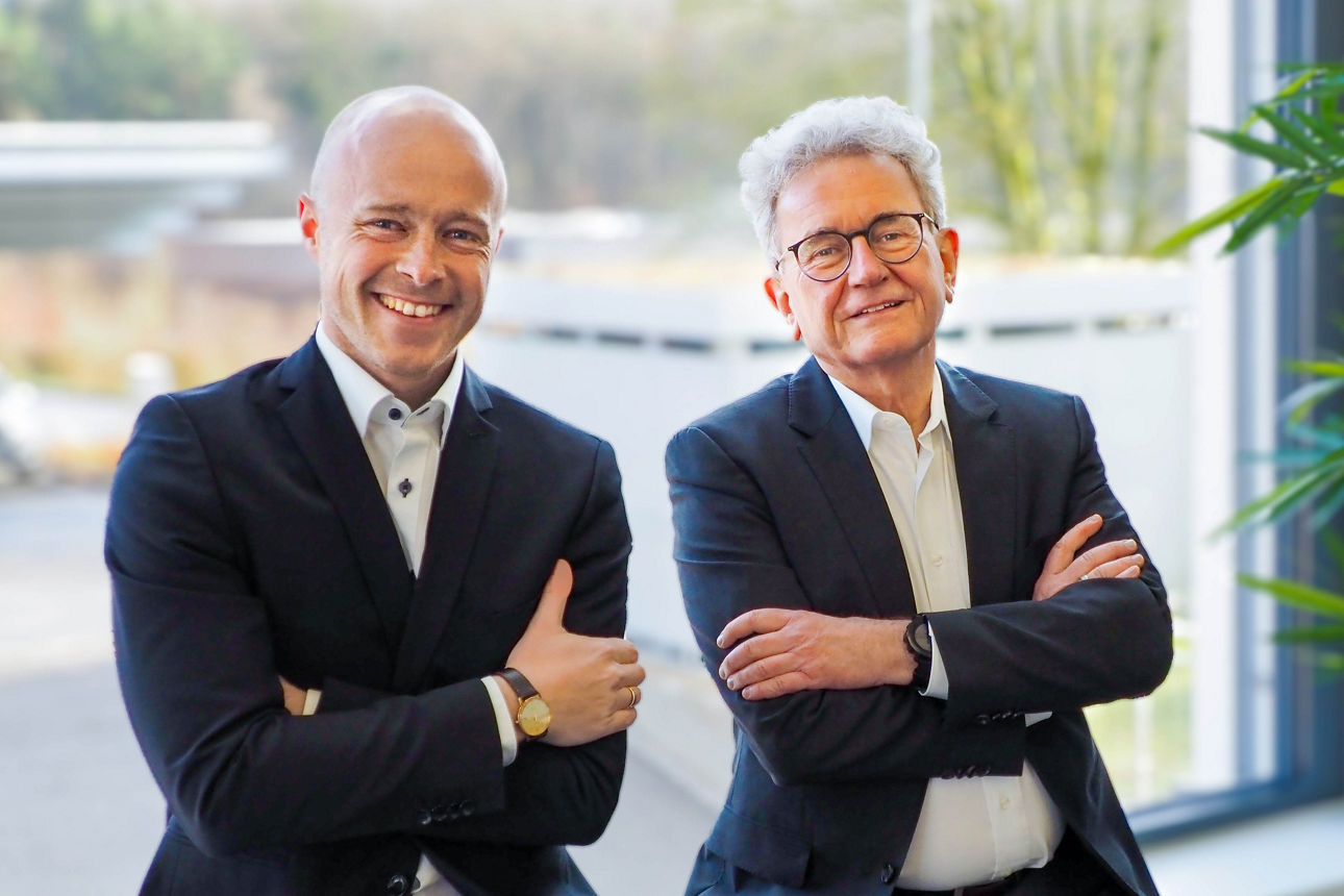 Zwei Männer lächeln freundlich in die Kamera