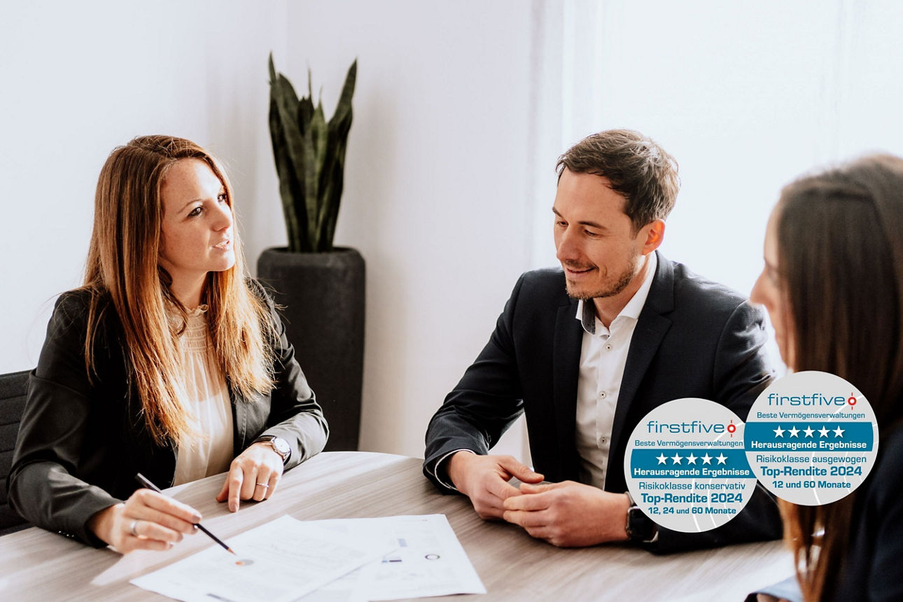 Drei Personen, die sich anschauen, sitzen an einem Tisch mit Unterlagen. Firstfive Siegel "Beste Vermögensverwaltung 2024"