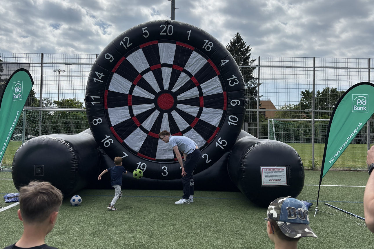Riesengroße aufblasbare Dartscheibe, Kinder mit Fußball im Vordergrund 