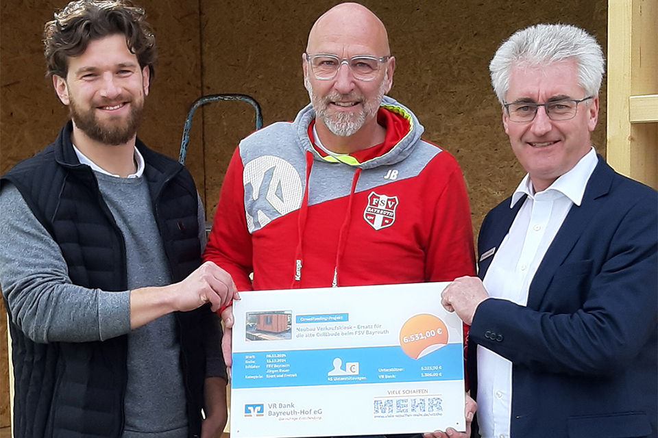Drei Männer halten die Crowdfunding-Tafel in den Händen