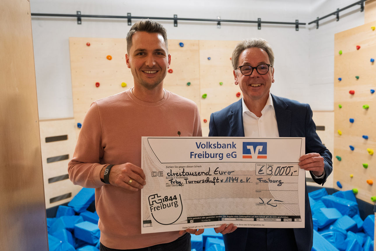 Zwei Personen halten einen großen Spendenscheck der Volksbank Freiburg über 3.000 € für die Freiburger Turnerschaft 1844 e.V.